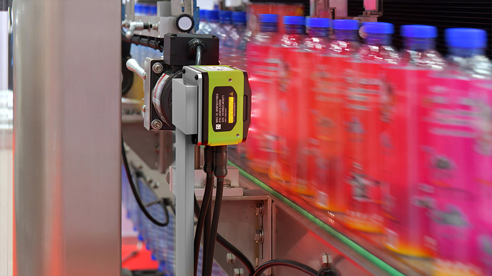 A fixed scanner positioned next to a production line, scanning bottles